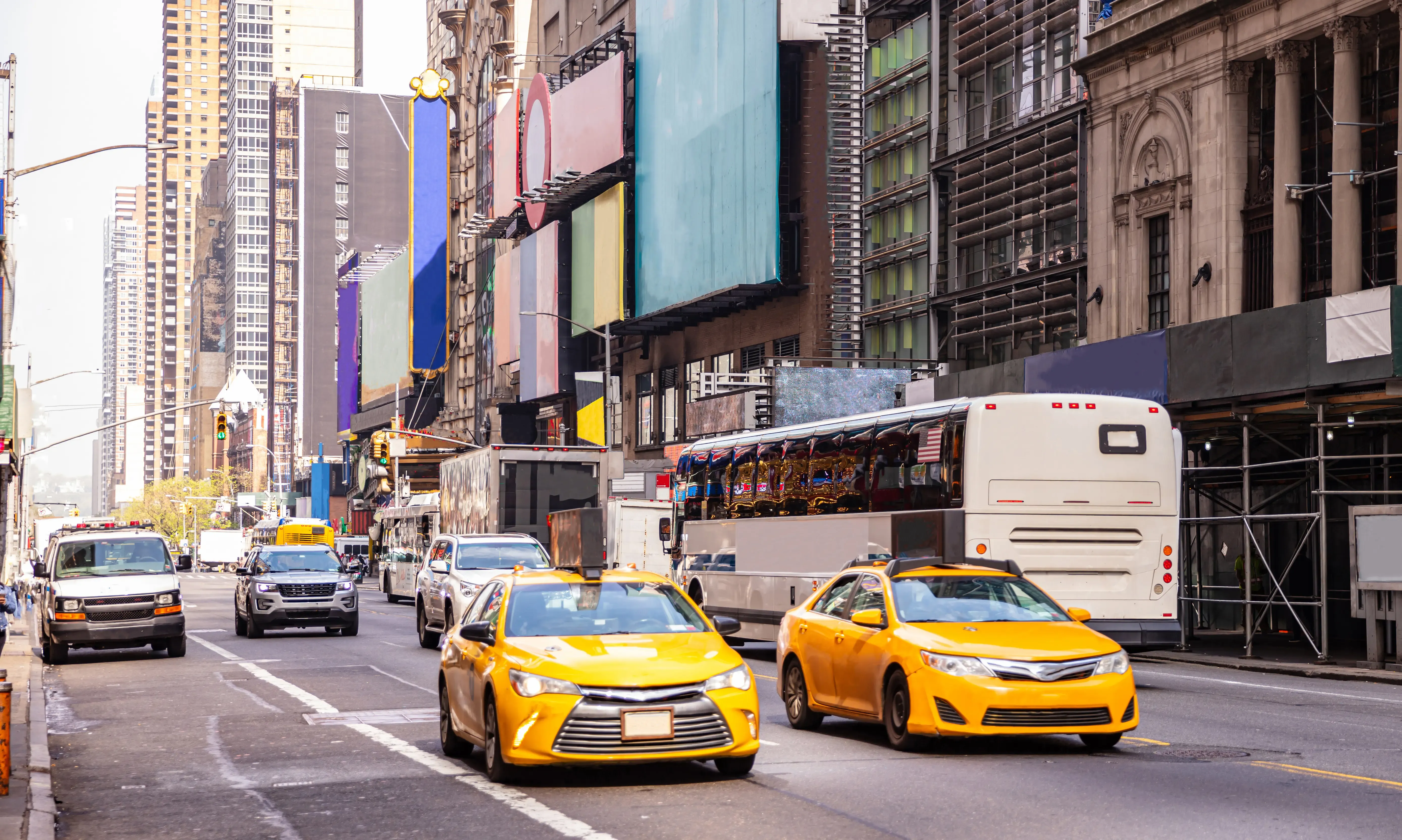 Busy New York City street lined with towering buildings and vibrant, colorful signs.